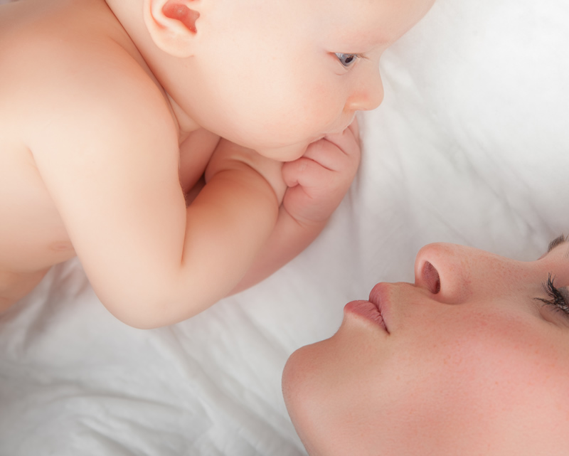 Newborn baby lying settled beside a parent