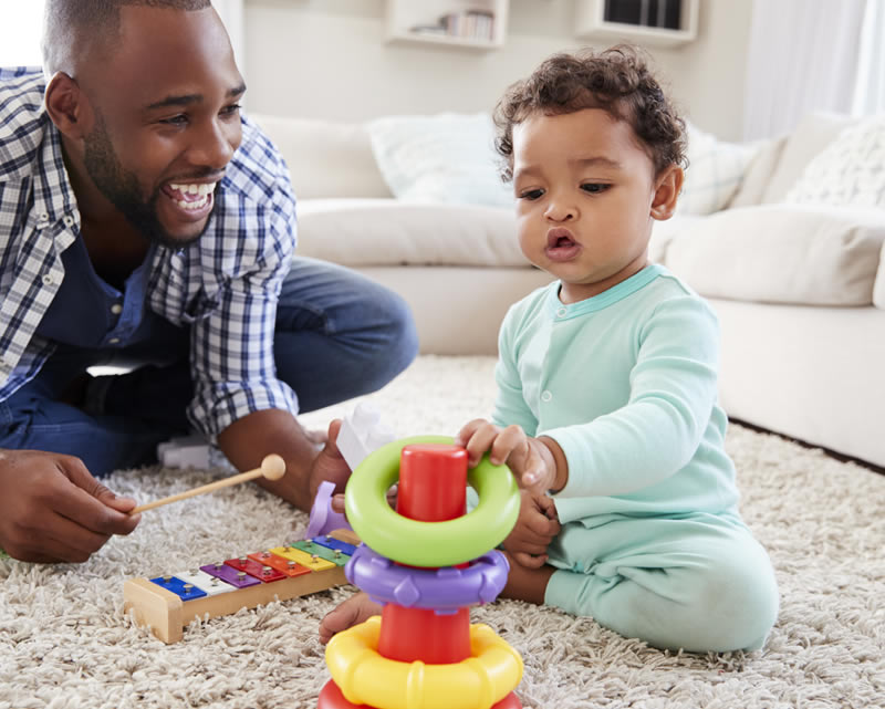 Toddler playing with wooden toys on the floor with an adult