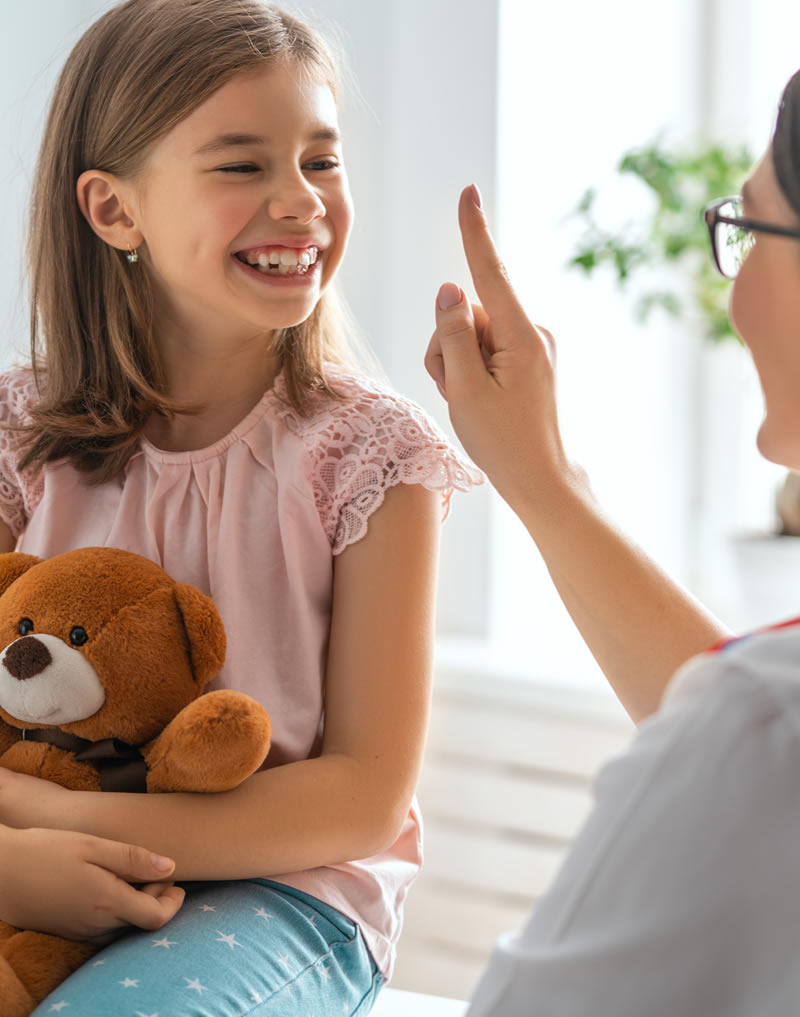 Young child holding a teddy bear beside a parent